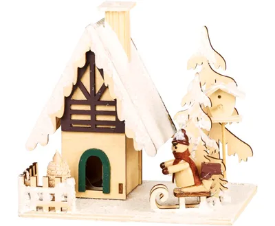 Ein Räucherhaus als winterliche Holzhütte, die mit Schnee bedeckt ist. Vorgarten mit Schlittenkind.