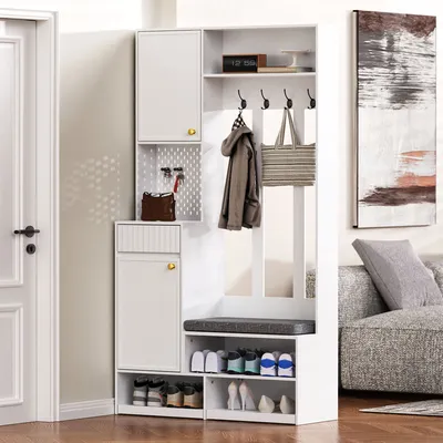 A white entryway furniture set with storage, a bench, and coat hooks, placed next to a door and a sofa.