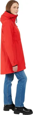 A woman wearing a red parka and blue jeans, shown from the side.