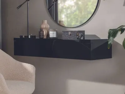 A black floating console table with decorative items on top, next to a chair and a mirror.