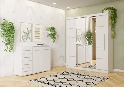 A white dresser and a white wardrobe with mirrored doors are displayed in a room with a textured white wall and a patterned rug.