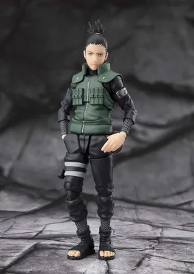 A full-body shot of an action figure of the character Shikamaru Nara from Naruto Shippuden, standing against a textured, dark background.