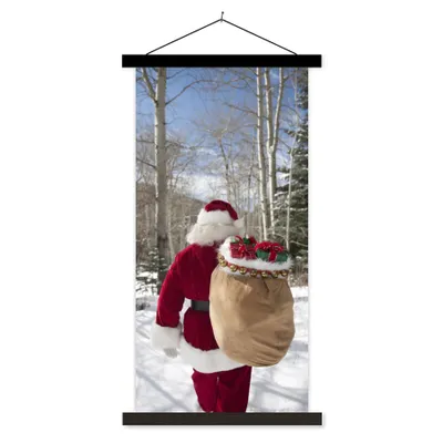 Produktbild von MuchoWow® Textilposter Der Weihnachtsmann geht mit einem Sack voller Weihnachtsgeschenke durch einen Wald 90x180 cm mit schwarzem Rahmen - Dekoration Wohnzimmer