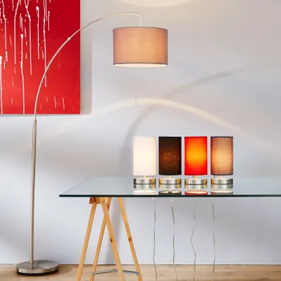 A modern interior setting with a floor lamp and several table lamps on a glass table.