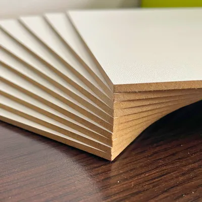 A stack of A4 sized white HDF boards fanned out on a dark wooden surface.