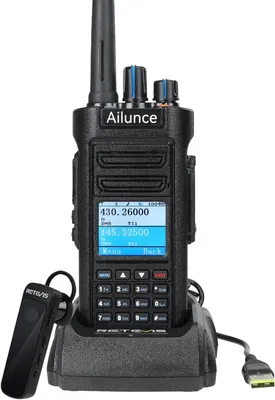 A Retevis Ailunce HD2 Ham Radio is shown in its charging cradle with a USB cable connected. A separate earpiece accessory is placed to the left of the radio.