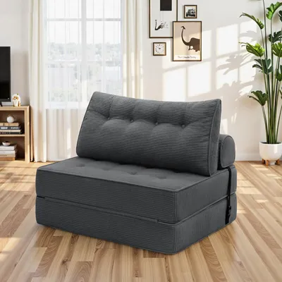 A gray foldable sofa bed is shown in a living room setting with a window and curtains in the background.