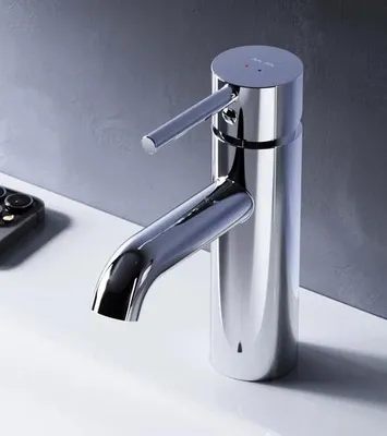A modern chrome faucet on a white sink with a gray wall in the background.
