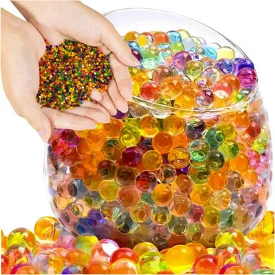 Hands holding small beads above a glass bowl filled with larger gel beads.