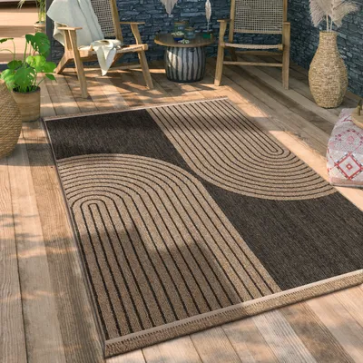 An outdoor patio setting with a rug on a wooden deck, chairs, and a table.