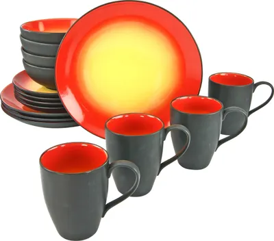 A set of stoneware dishes and mugs with a gradient of red and yellow on the plates and red interiors on the mugs.