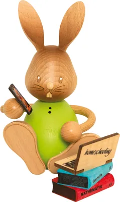 A wooden figurine of a rabbit sitting with a laptop and books.