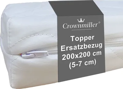 A close-up view of a white mattress topper cover with a dark grey band wrapped around it, displaying product information.