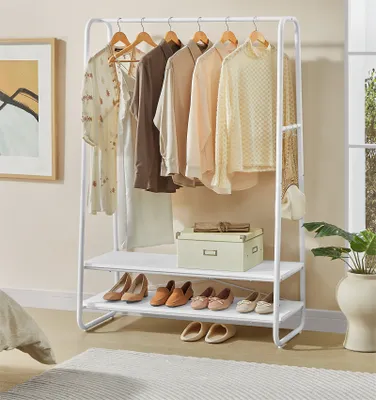 A white garment rack with clothes hanging on it and shoes on the shelves below.