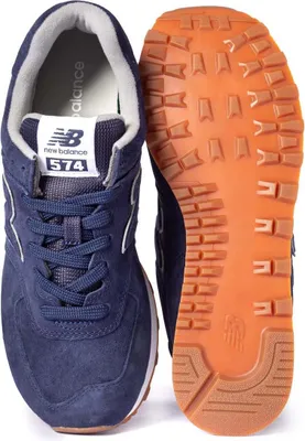 A pair of New Balance 574 sneakers, shown from a top-down perspective, with one shoe upright and the other lying on its side to reveal the sole.