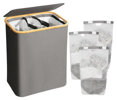 A grey laundry basket with a wooden rim and lid, shown with three separate laundry bags next to it.