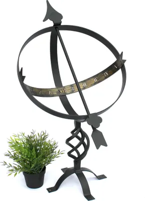 A black metal sundial on a stand, with a small potted plant to the left.
