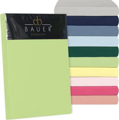 A stack of folded bed sheets in various colors, with one sheet prominently displayed in the foreground, partially covered by packaging.