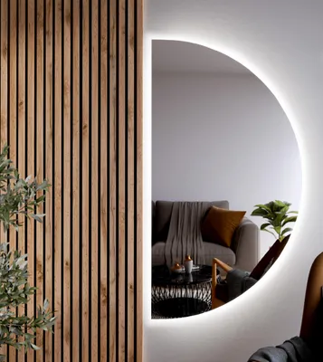 A modern bathroom interior with a semi-circular LED mirror reflecting a living room scene.