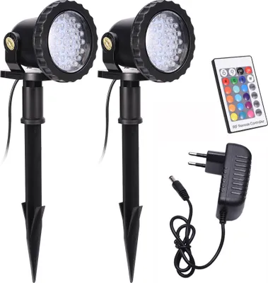 Two black garden spotlights with stakes, a remote control, and a power adapter are arranged on a white background.