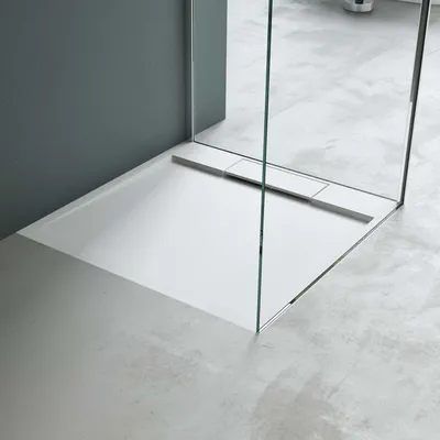 A modern, minimalist shower tray with a glass shower enclosure.
