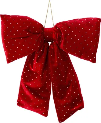 A large red bow with white polka dots, hanging from a thin gold string.