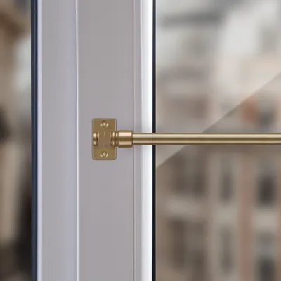 Close-up of a brass cafe curtain rod attached to a window frame.