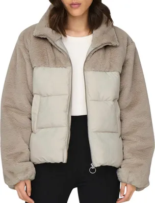 A woman wearing a beige and cream puffer jacket.
