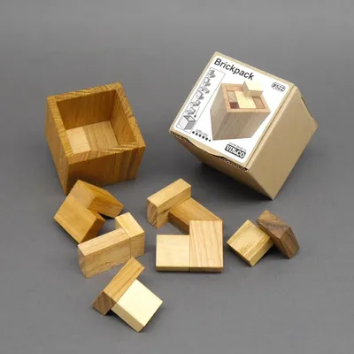 Brickpack Holzpuzzle: offene Holzbox mit verstreuten Puzzleteilen auf grauem Hintergrund.