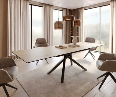 A modern dining room with a large extendable table and chairs, set against a backdrop of large windows with curtains.