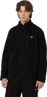 A man wearing a black fleece jacket and black pants, standing against a white background.