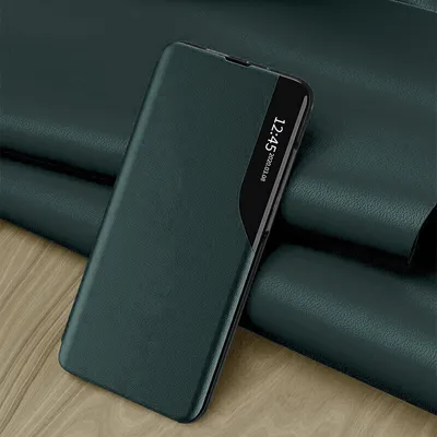 A dark green phone case with a transparent window displaying the time and date is placed on a textured dark green surface and a wooden surface.