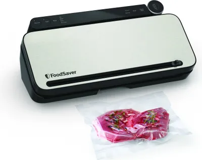 A FoodSaver vacuum sealer with a piece of meat vacuum-sealed in plastic in front of it.