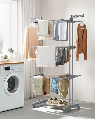 A laundry room scene with a washing machine and a multi-tiered drying rack filled with clothes.