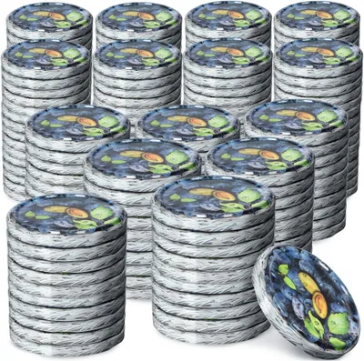 Stacks of metal canning lids with a colorful design on top.