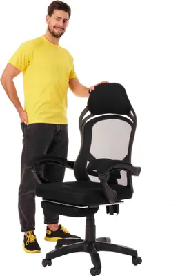 A man stands next to a black gaming chair.