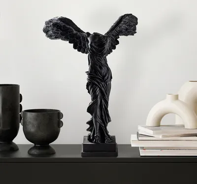 A black statue of Nike, the Greek goddess of victory, is displayed on a black shelf.