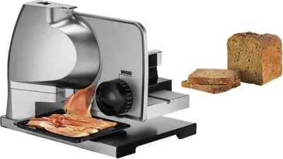 A food slicer with sliced ham and a loaf of bread.