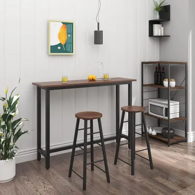A bar table and two stools in a room with white paneled walls and wooden flooring.