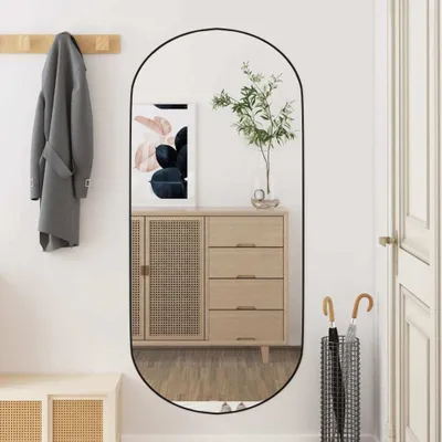 A hallway with a mirror reflecting a dresser and a coat hanging on a rack.