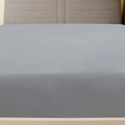 A close-up view of a grey fitted sheet on a bed.