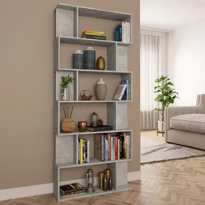 A tall, narrow bookshelf filled with books and decorative items, placed against a wall in a room with a sofa and a plant visible in the background.