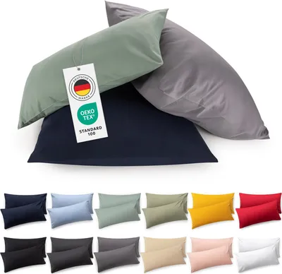 A collection of pillowcases in various colors, with a close-up of three pillowcases in navy blue, sage green, and gray at the top, featuring a tag with certifications.