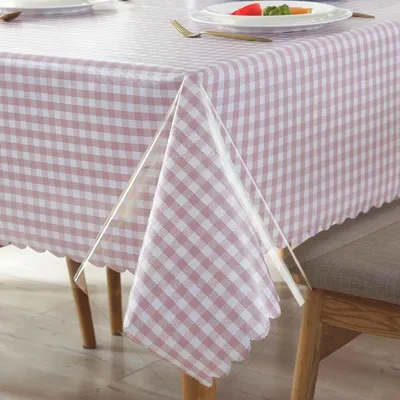 A close-up of a table covered with a pink and white checkered tablecloth, with a clear plastic overlay draped over a corner.