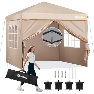 A woman is walking and carrying a folded tent bag in front of an open tent.