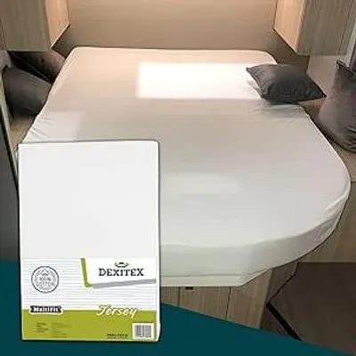 A white fitted sheet is shown on a bed, likely in a campervan or caravan, with a packaging box in the foreground.