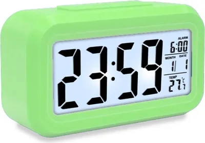 A green digital alarm clock with a white display showing the time, date, alarm, and temperature.