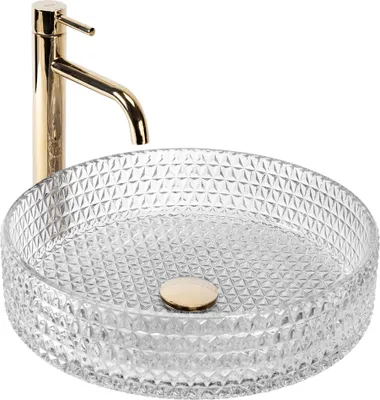 A clear studio shot of a glass vessel sink with a gold faucet.
