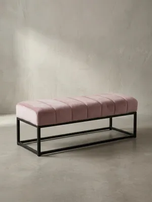 Frontansicht der Design-Sitzbank mit rosa Samtpolster und minimalistischem schwarzem Metallgestell, freigestellt vor weißem Hintergrund._#sku_SAFWL7.011#
