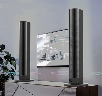 Two tall black speakers are placed on a cabinet in front of a television displaying a racing car.